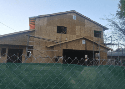 A house under construction with a chain link fence.