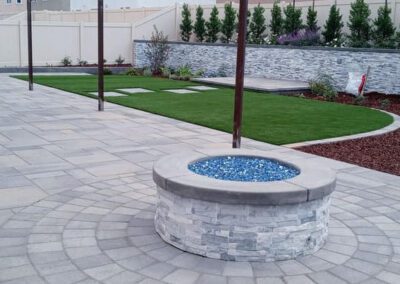 A backyard with a fire pit and grass.